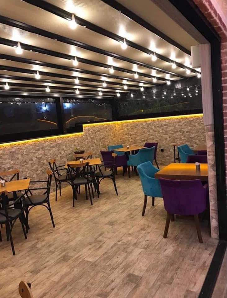 Ahşap tavanlı, ışıklı kış bahçesinde mor ve turkuaz koltuklar